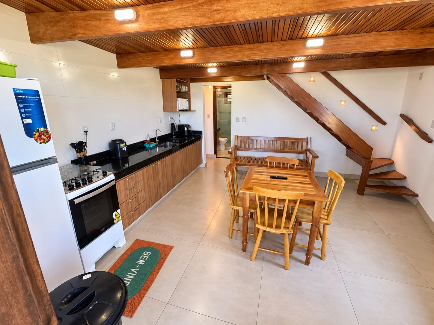Cozinha e sala de jantar do bangalô, com a escada de madeira do mezanino